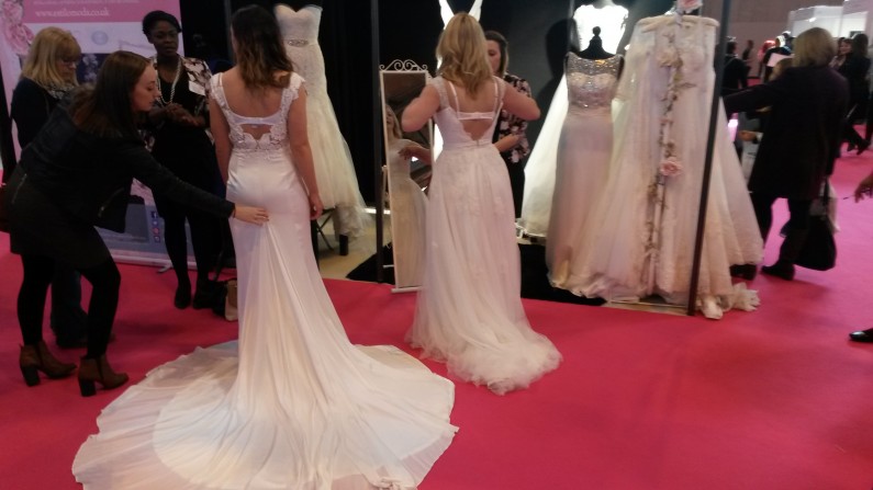 Brides trying on dresses at Estilo Moda Bridal Stand at The National Wedding Show Birmingham NEC